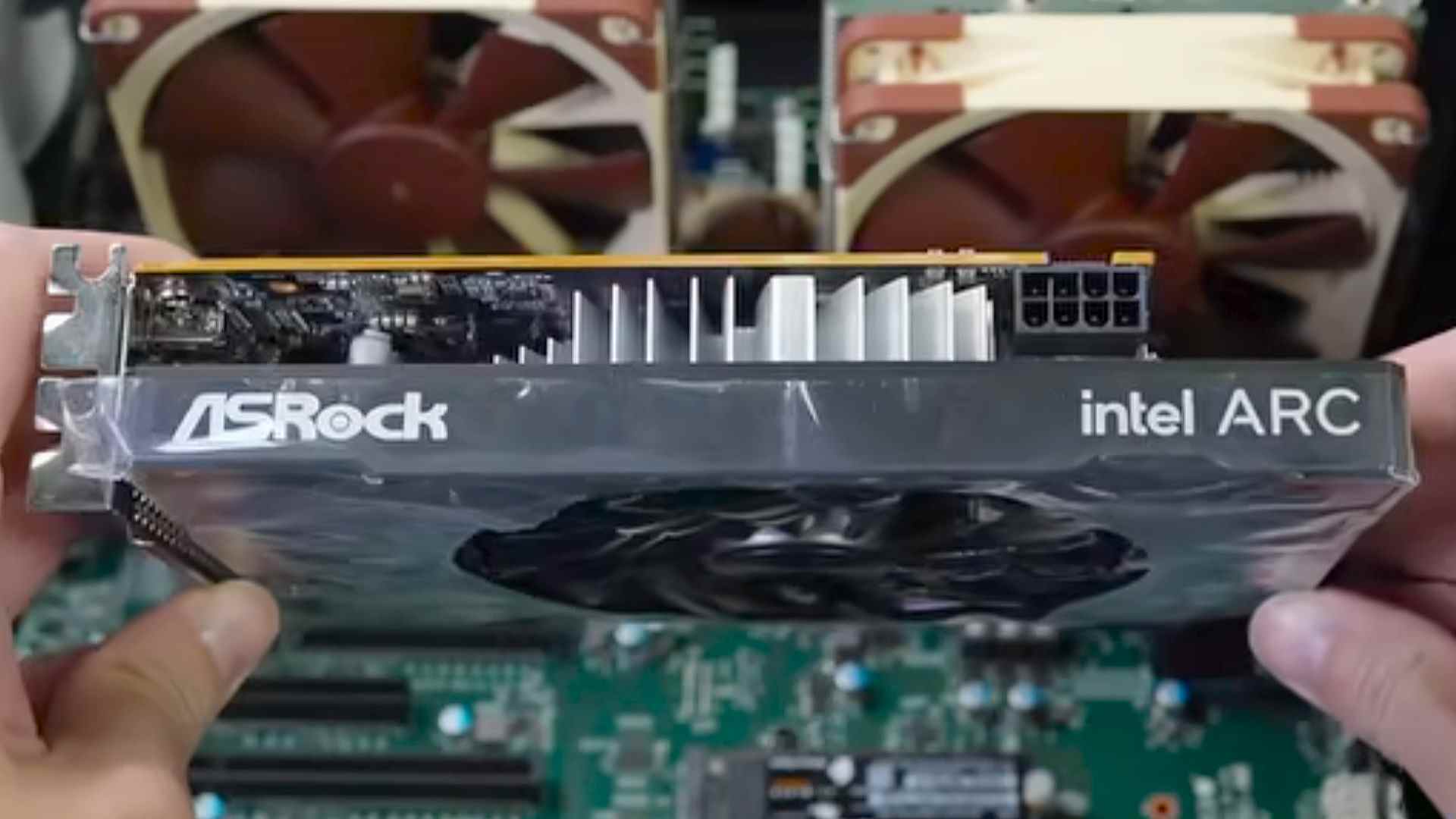 hands holding ASRock Intel ARC GPU over motherboard