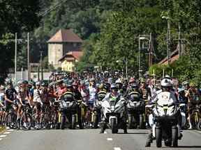 Le peloton de coureurs est temporairement immobilisé par les régulateurs de course (avant) en raison d'une action de protestation sur le parcours lors de la 10e étape de la 109e édition du Tour de France cycliste, 148,1 km entre Morzine et Megève, dans les Alpes françaises , le 12 juillet 2022.