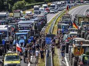 Des agriculteurs se rassemblent avec leurs véhicules à côté d'un panneau frontalier Allemagne/Pays-Bas lors d'une manifestation sur l'autoroute A1, près de Rijssen, le 29 juin 2022, contre les plans d'azote du gouvernement néerlandais.  (Photo de Vincent Jannink / ANP / AFP)