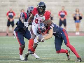 Llevi Noel, au centre, des Redblacks d'Ottawa, est attaqué par Davis Alexander (6) et Marc-Antoine Dequoy (24) des Alouettes de Montréal lors de l'action de football d'avant-saison de la LCF contre les Alouettes de Montréal à Montréal, le vendredi 3 juin 2022 .