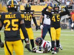 Le secondeur des Tiger Cats de Hamilton Jovan Santos-Knox (45 ans) célèbre son tacle contre le porteur de ballon des Alouettes de Montréal Jeshrun Antwi (20 ans) lors de la première mi-temps du match de football de la LCF à Hamilton le 28 juillet 2022.