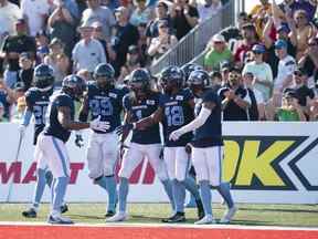 Wynton McManis des Argonauts de Toronto, deuxième à partir de la droite, célèbre avec ses coéquipiers après avoir repoussé un touché sur une interception lors de la deuxième moitié de l'action de la LCF contre les Roughriders de la Saskatchewan à l'Université Acadia de Wolfville, en Nouvelle-Écosse, le samedi 16 juillet 2022.