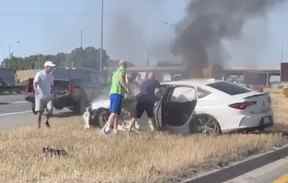 Un groupe d'automobilistes du Bon Samaritain sauve un homme d'une voiture en feu sur une section du QEW à Mississauga à Cawthra Road le 4 juillet 2022. OPP_HSD/TWITTER