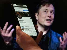 Un écran de téléphone affiche le compte Twitter d'Elon Musk avec une photo de lui en arrière-plan.  Musk a déclaré vendredi qu'il mettait fin à son contrat de 44 milliards de dollars avec Twitter Inc.