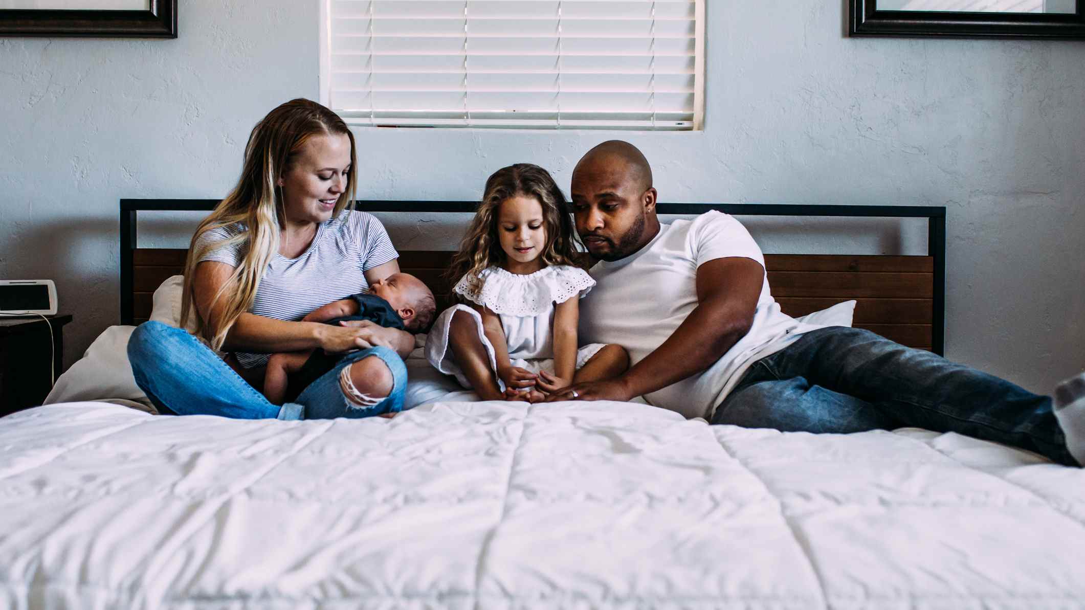 Une jeune famille de quatre personnes s'allonge ensemble sur un matelas king size