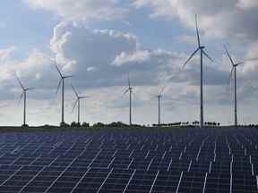 Des éoliennes tournent derrière un parc d'énergie solaire près de Prenzlau, en Allemagne.