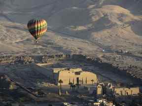 Un ballon à air chaud survole le temple funéraire de Ramsis III à Médinet Habou sur la rive ouest du Nil à Louxor, Egypte