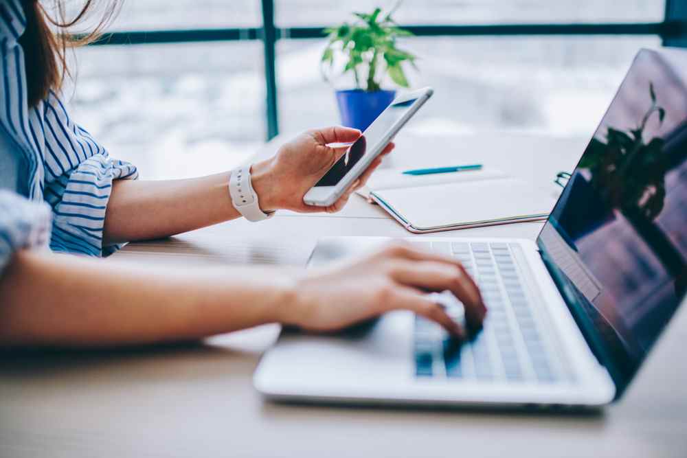 Femme utilisant un smartphone et un ordinateur portable