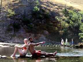 Les gens s'assoient dans la rivière Dove à Dovedale pendant la canicule, Derbyshire, Grande-Bretagne, le 19 juillet 2022.