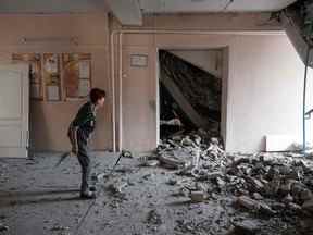 Un enseignant examine la destruction d'une école détruite à la suite d'un bombardement à Bakhmut, dans la région de Donetsk, le 24 juillet 2022.