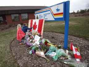 Des enfants signent un drapeau canadien lors d'un mémorial impromptu devant le détachement de la GRC le 20 avril 2020 à Enfield, en Nouvelle-Écosse.