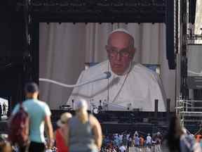 Les gens regardent un écran pendant que le pape François prononce un discours à la Citadelle de Québec le mercredi 27 juillet 2022.