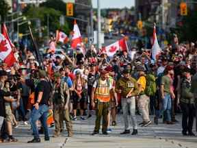 Le réserviste de l'armée James Topp, au centre, arrive au Monument commémoratif de guerre du Canada lors d'une manifestation contre les mesures de santé liées à la COVID-19 au Monument commémoratif de guerre du Canada à Ottawa, en Ontario.  le jeudi 30 juin 2022. Topp dit qu'il ne croit pas que les gens auraient prêté attention s'il n'avait pas enfilé son uniforme pour s'opposer publiquement aux exigences de l'armée canadienne en matière de vaccins. LA PRESSE CANADIENNE/Spencer Colby