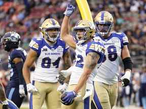 Drew Wolitarsky des Blue Bombers de Winnipeg célèbre son touché avec ses coéquipiers Geoff Gray (à droite) et Brendan O'Leary-Orange lors de la première mi-temps contre les Argonauts de Toronto lundi au BMO Field.