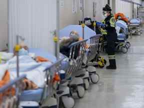 Les ambulanciers paramédicaux transfèrent les patients au triage des urgences mais n'ont d'autre choix que de les laisser dans le couloir en raison d'une salle d'urgence à pleine capacité à l'hôpital Humber River pendant la pandémie de COVID-19 à Toronto le mardi 25 janvier 2022. LA PRESSE CANADIENNE /Nathan Denette