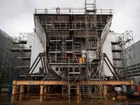 Un travailleur se tient debout sur un navire de soutien interarmées en construction pour la Marine royale canadienne aux chantiers navals Seaspan à North Vancouver, en Colombie-Britannique, en octobre 2020.