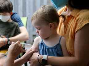 Beatrice Giles, deux ans, regarde avec méfiance l'aiguille alors qu'elle est assise sur les genoux de sa mère Kristina Pawk pendant qu'elle se fait vacciner.  Son frère aîné Theo Giles, 4 (arrière) a également obtenu le sien lors de l'événement.  Le Dr Nili Kaplan-Myrth a tenu une "Jabapalooza" événement de vaccination de masse contre la COVID dans le stationnement derrière le cabinet de son médecin dans le Glebe jeudi.  Julie Oliver/Postmédia