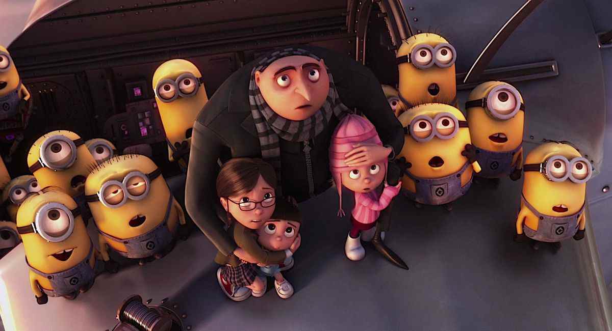 L'anti-héros animé Gru abrite ses trois orphelins adoptés dans ses bras tout en étant entouré de Minions, alors que tout le monde sur l'image regarde vers le haut avec la bouche ouverte dans Despicable Me.