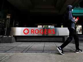 Une personne passe devant l'immeuble de Rogers Communications à Toronto.