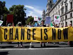 Des manifestants tiennent des pancartes et des banderoles alors qu'ils participent à une marche de protestation arrivant sur la place du Parlement, à Londres, le 23 juillet 2022 pour exiger des mesures contre la crise du coût de la vie et la crise du changement climatique.