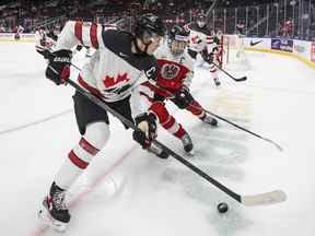 Le Canadien Kaiden Guhle (21 ans) et l'Autrichien Marco Kasper (19 ans) se battent pour la rondelle lors de la première période du Championnat mondial de hockey junior de l'IIHF à Edmonton le mardi 28 décembre 2021.