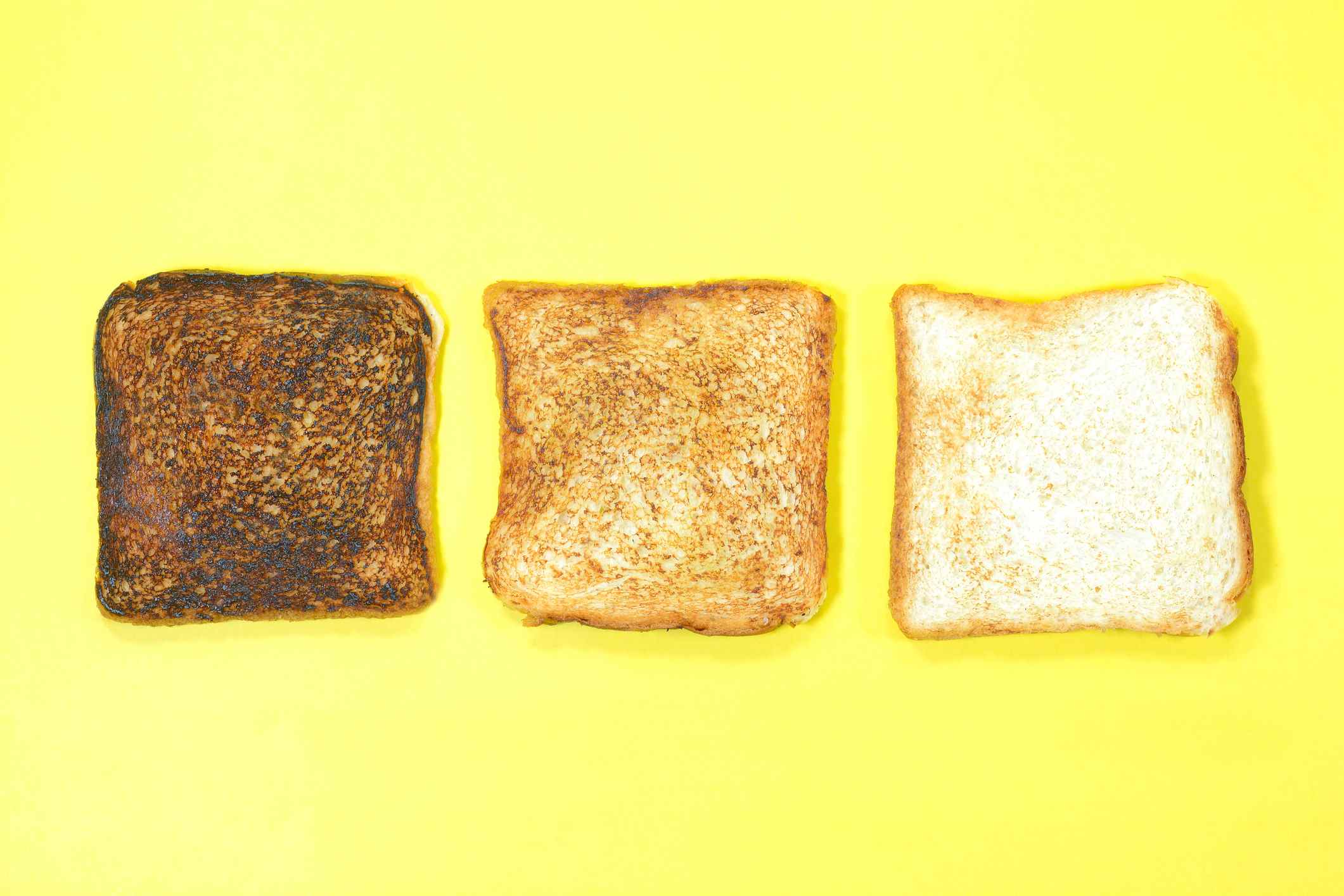 Tranche de pain mal brûlée, grillée à juste titre et ordinaire sur fond jaune.