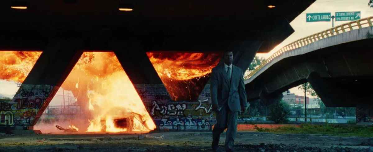 Creasy s'éloigne d'une voiture en flammes sous un passage souterrain dans Man on Fire.