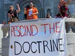 À l'extérieur du Sanctuaire de Sainte-Anne-de-Beaupré, des gens tiennent une banderole sur laquelle on peut lire « Abroger la doctrine ».  Gracieuseté du chef algonquin Lance Haymond/via REUTERS