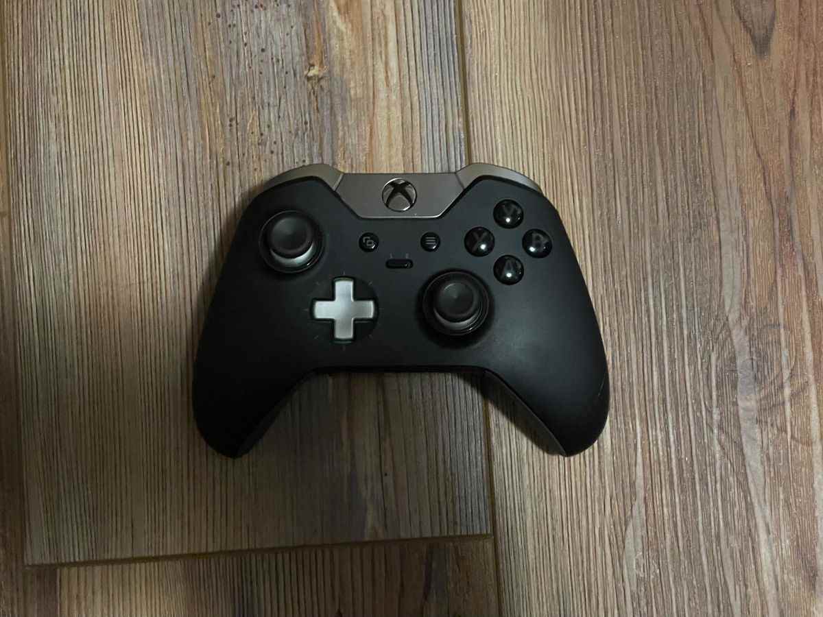 Une manette Xbox Elite Series 1 est posée sur un sol en bois