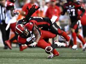 Le receveur large des Stampeders de Calgary Kamar Jorden (88) grimace alors qu'il est plaqué par le demi défensif des Redblacks d'Ottawa Abdul Kanneh (14) lors de la première mi-temps de l'action de football de la LCF à Ottawa le vendredi 5 août 2022.