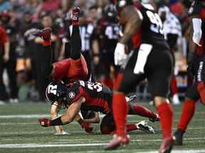 Le receveur éloigné des Stampeders de Calgary Colton Hunchak (89) se fait renverser après un tacle du secondeur des Redblacks d'Ottawa Adam Auclair (32) lors de la première mi-temps de l'action de football de la LCF à Ottawa le vendredi 5 août 2022.