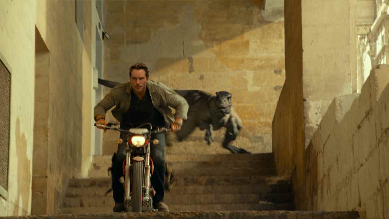 Chris Pratt s'éloigne d'un Atrociraptor sur une moto dans Jurassic World Dominion.