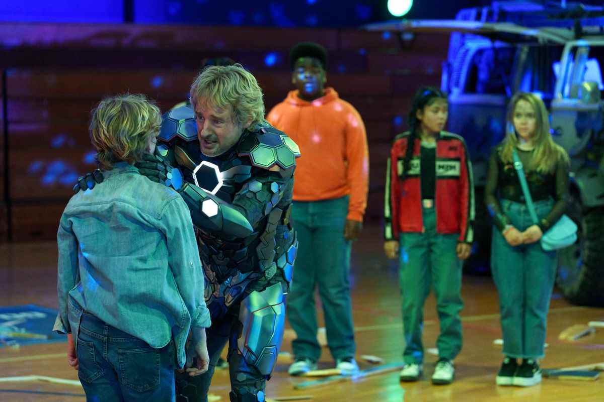 Owen Wilson en armure Iron Man, réconfortant un enfant blond