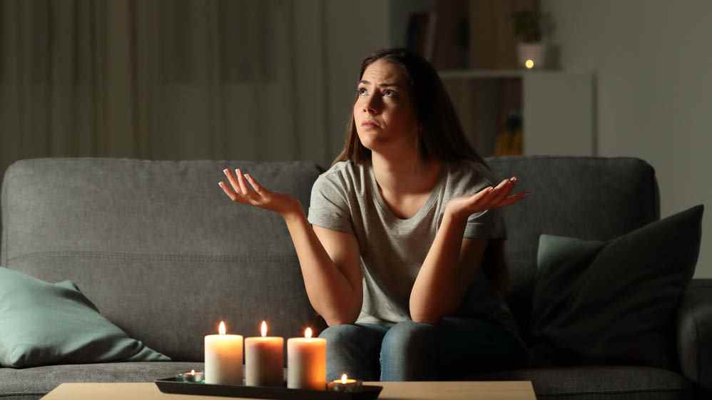 Quelqu'un assis à la maison sans rien faire pendant une panne de courant, avec des bougies sur une table