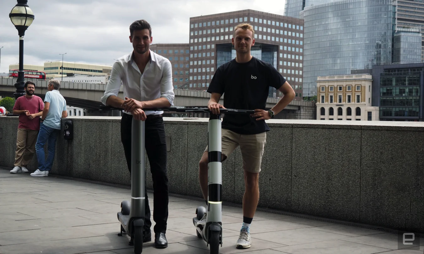 Les co-fondateurs de Bo Mobility, Oscar Morgan (à gauche) et Harry Wills (à droite), debout à cheval sur deux prototypes de scooter électrique Bo.