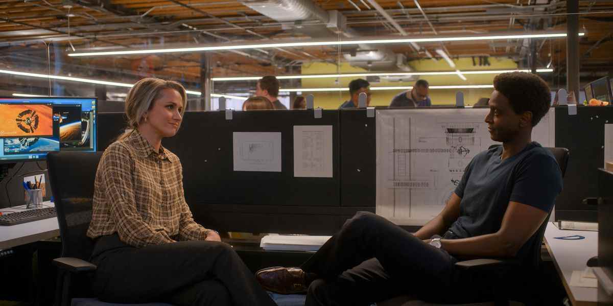 Karen et Dev assis dans une cabine de bureau se sourient