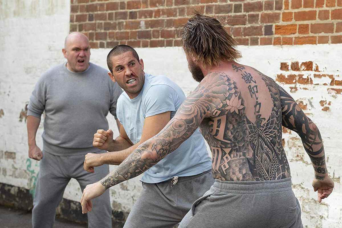 Scott Adkins donne un coup de poing dans une cour de prison dans Avengement