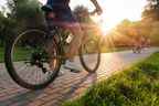 Un homme fait du vélo à l'extérieur dans le parc par une journée ensoleillée au coucher du soleil.