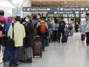 Les gens font la queue avant d'entrer dans la sécurité à l'aéroport international Pearson de Toronto le vendredi 5 août 2022. Le comité des transports de la Chambre des communes tient une réunion d'urgence aujourd'hui pour discuter de l'opportunité de poursuivre une enquête sur les retards de l'aéroport et les annulations de vols. LA PRESSE CANADIENNE/Nathan Denette