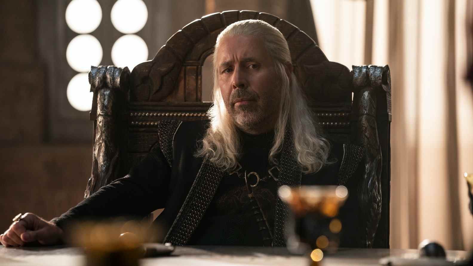 Le roi Viserys I de Paddy Considine est assis à une table pour discuter de questions dans House of the Dragon