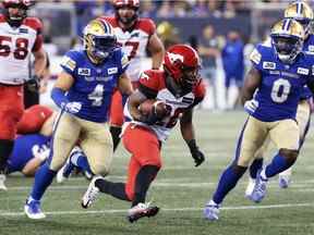 Le demi offensif des Stampeders Peyton Logan est poursuivi par les secondeurs des Blue Bombers Adam Bighill (à gauche) et Malik Clements lors du match de jeudi.