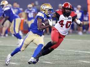 Le demi-fendu des Blue Bombers Greg McRae est poursuivi par le joueur de ligne défensif des Stampeders Shawn Lemon lors du match de jeudi.