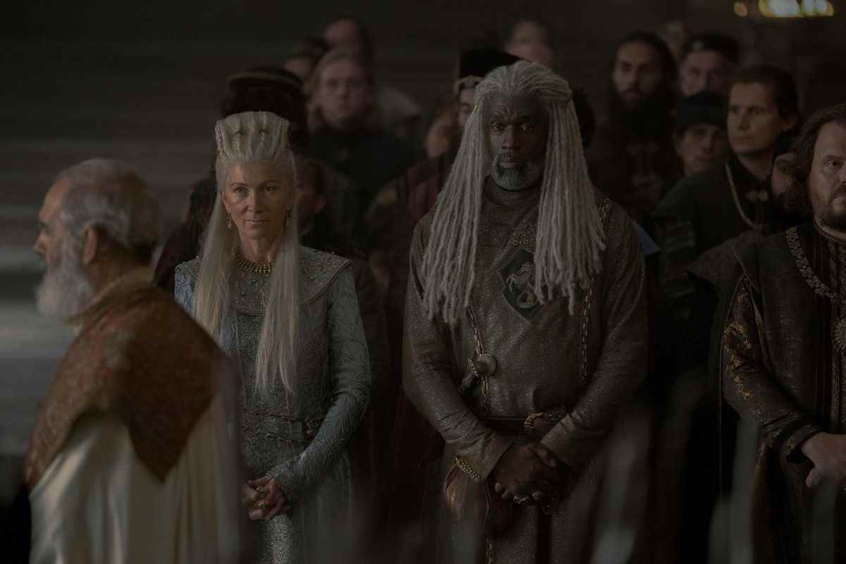 Rhaenys Targaryen se tient à côté de son mari Corlys Velaryon parmi une foule de personnes à la cour de House of the Dragon.