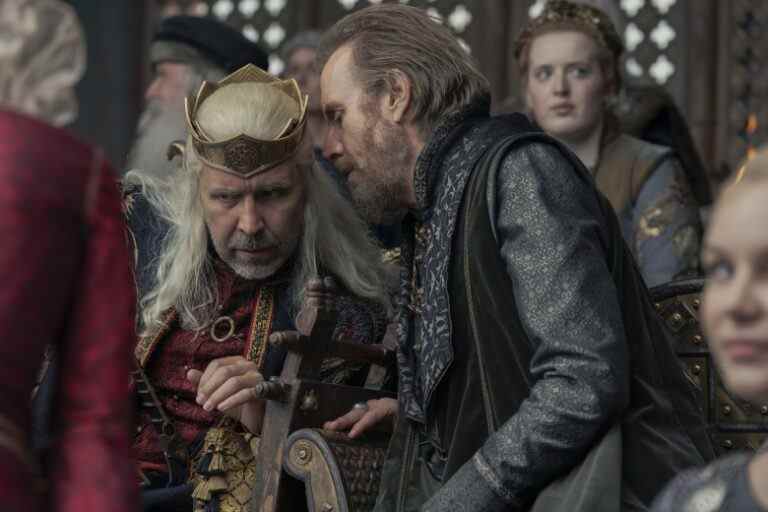 A man with light brown hair whispers in the ear of a medieval king with long white-blond hair; still from "House of the Dragon."