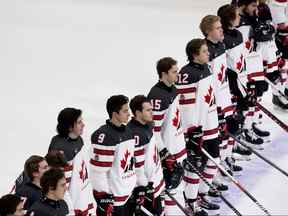 Dans cette photo d'archive du 28 décembre 2021, des membres d'Équipe Canada regardent le drapeau canadien être hissé après leur victoire contre l'équipe d'Autriche au Championnat mondial de hockey junior de l'IIHF à Edmonton.