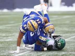 Les ailiers défensifs des Blue Bombers de Winnipeg Jackson Jeffcoat (en haut) et Willie Jefferson affrontent le QB Cody Fajardo des Roughriders de la Saskatchewan.