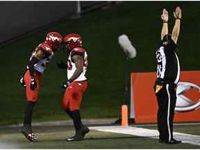 Le demi défensif des Stampeders de Calgary Titus Wall (32) célèbre son touché avec le joueur de ligne défensive Shawn Lemon (40) après avoir intercepté le ballon du quart-arrière des Redblacks d'Ottawa Caleb Evans (5), non montré, lors de la première mi-temps de l'action de football de la LCF à Ottawa le vendredi 28 août. 5, 2022.