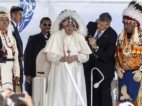 Le pape François reçoit une coiffe traditionnelle après s'être excusé pour le rôle de l'Église catholique romaine dans le système des pensionnats, à Maskwacis, en Alberta, lors de sa visite papale à travers le Canada le lundi 25 juillet 2022.