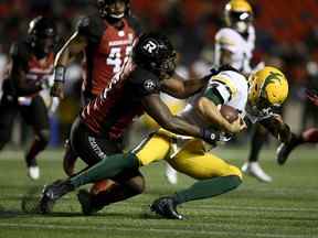 Le joueur de ligne défensive des Redblacks d'Ottawa, Louange Martin-Oguike (95 ans), s'attaque au quart-arrière des Elks d'Edmonton Taylor Cornelius (15 ans) lors de la première mi-temps de l'action de football de la LCF à Ottawa le mardi 28 septembre 2021.