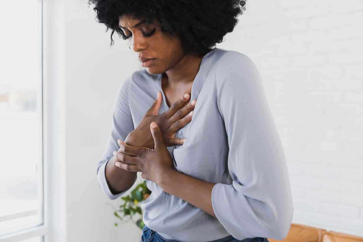 Femme avec les deux mains sur le dessus de la poitrine ressentant de la douleur